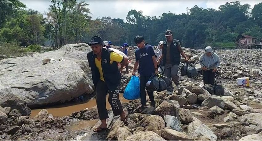 Warga dan Relawan Seberangi Sungai Penuh Batu di Sumbar